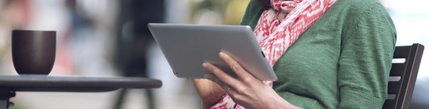 A smiling woman working on her tablet computer at an outdoor cafe